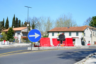 Photo of Street with road sign One Way Traffic, plastic safety barrier and temporary yellow markings on sunny day. Construction works