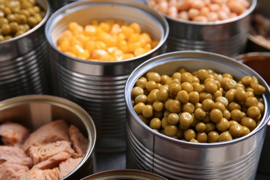 Photo of Open tin cans with conserved products, closeup