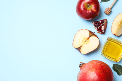 Photo of Honey, apples and pomegranates on light blue background, flat lay with space for text. Rosh Hashanah holiday