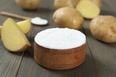 Photo of Starch and fresh potatoes on wooden table, closeup