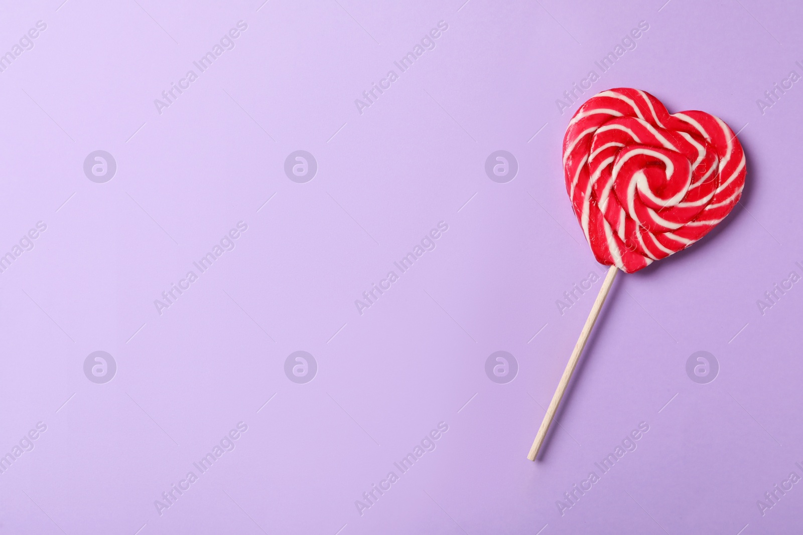 Photo of Sweet heart shaped lollipop on violet background, top view with space for text. Valentine's day celebration
