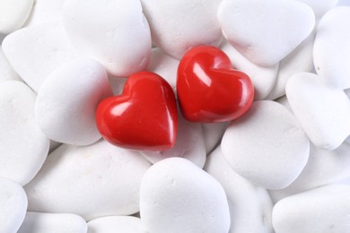 Photo of Decorative hearts on white pebble stones, top view
