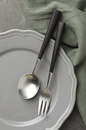 Photo of Stylish setting with cutlery, napkin and plate on grey textured table, top view