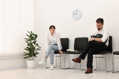 Man and woman waiting for job interview indoors