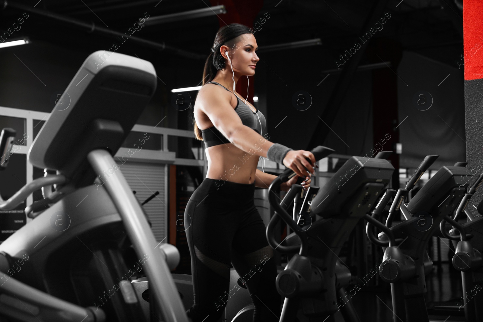 Photo of Young woman working out on elliptical trainer in modern gym