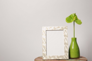 Blank frame and vase with flower on table against white background. Mock up for design