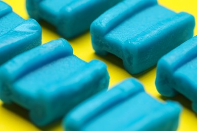 Photo of Blue bubble gums on yellow background, closeup
