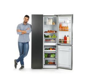 Photo of Young man near open refrigerator on white background