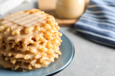 Plate of waffles and condensed milk on grey table, closeup with space for text. Dairy product