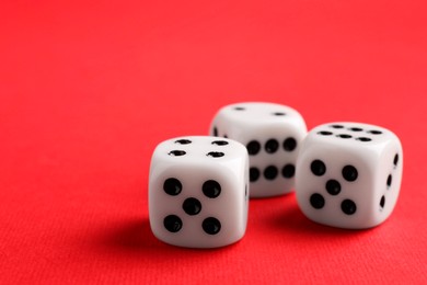 Photo of Three white game dices on red background, closeup