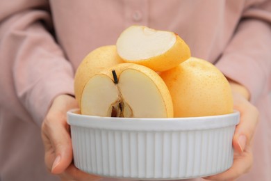 Woman holding bowl with fresh cut apple pears, closeup