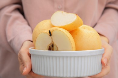 Photo of Woman holding bowl with fresh cut apple pears, closeup