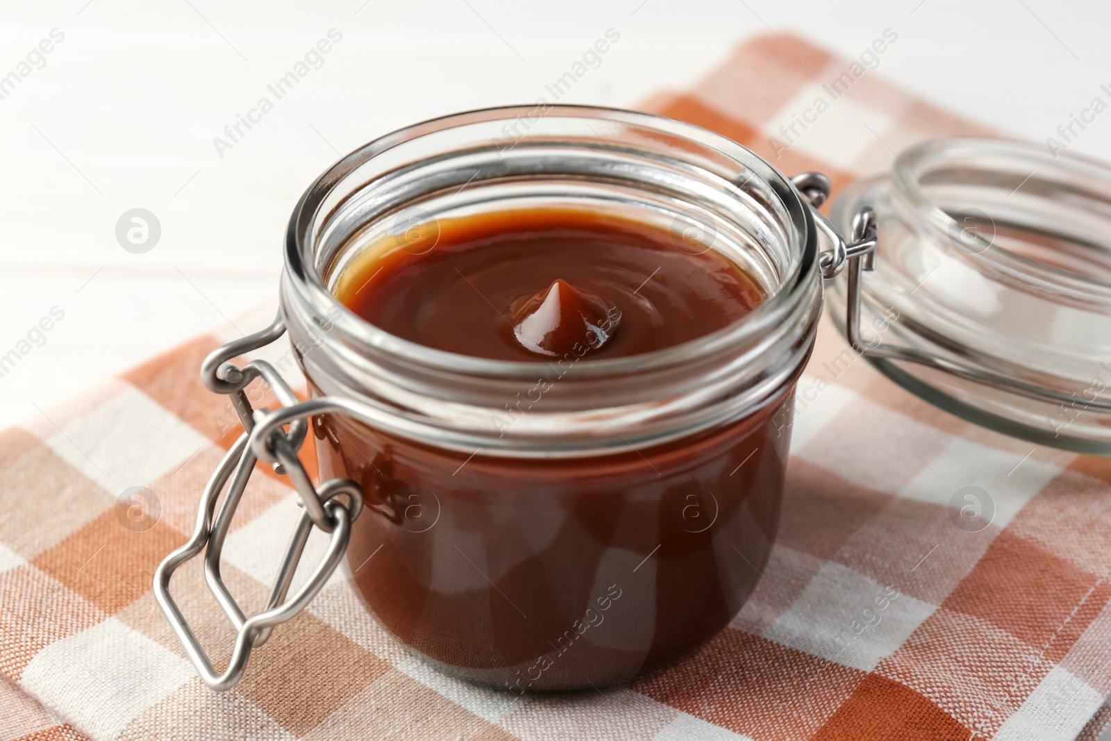 Photo of Tasty barbecue sauce in glass jar on table, closeup