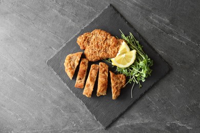 Photo of Tasty schnitzels served with microgreens and lemon on grey table, top view