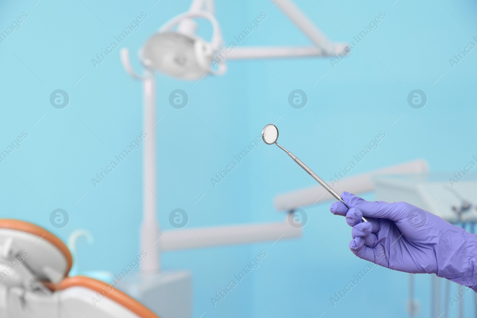 Photo of Dentist holding mirror in clinic, closeup of hand. Space for text