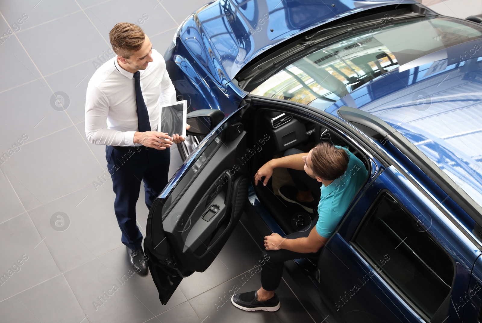 Photo of Young car salesman working with client in dealership