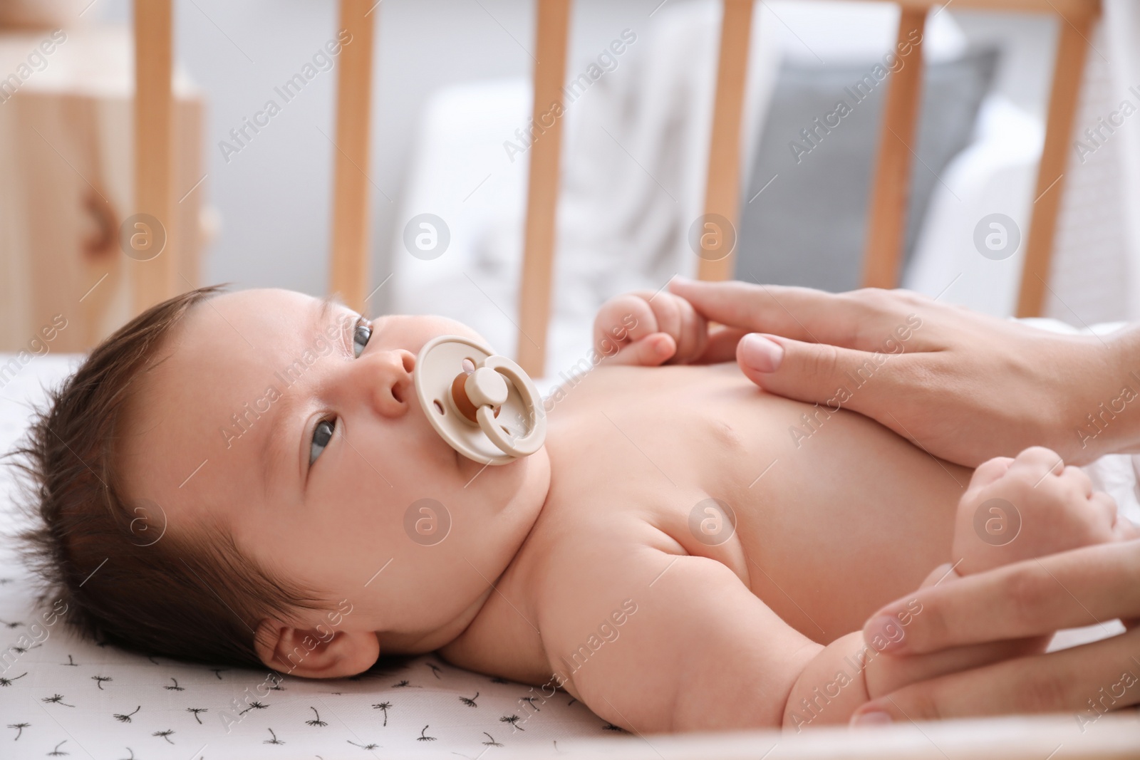 Photo of Cute little baby with pacifier in crib at home