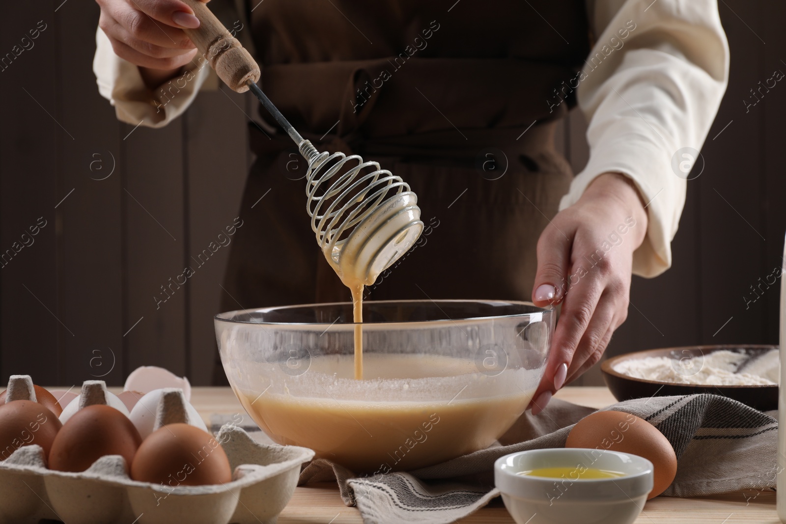 Photo of Woman making dough with whisk in bowl at table, closeup