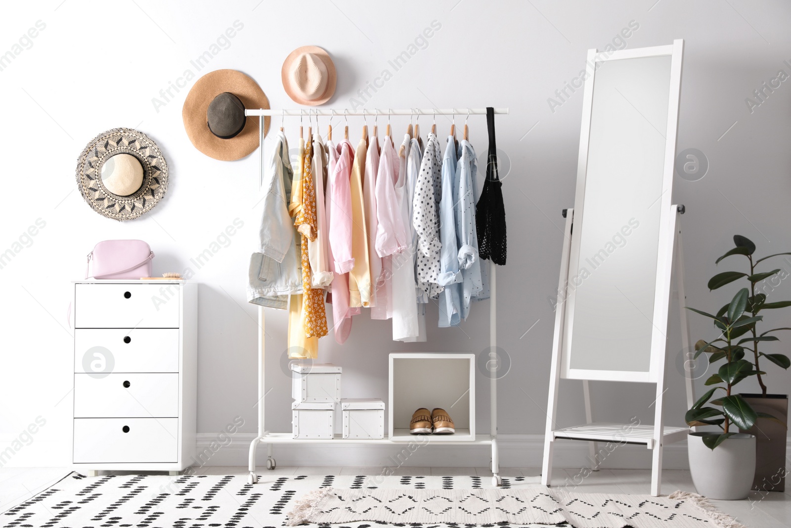 Photo of Rack with stylish women's clothes and mirror indoors. Interior design