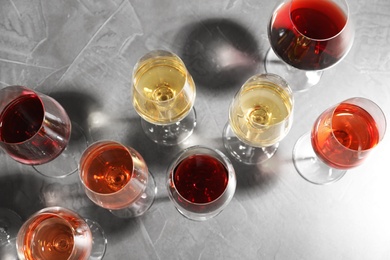 Photo of Different glasses with wine on grey background, flat lay