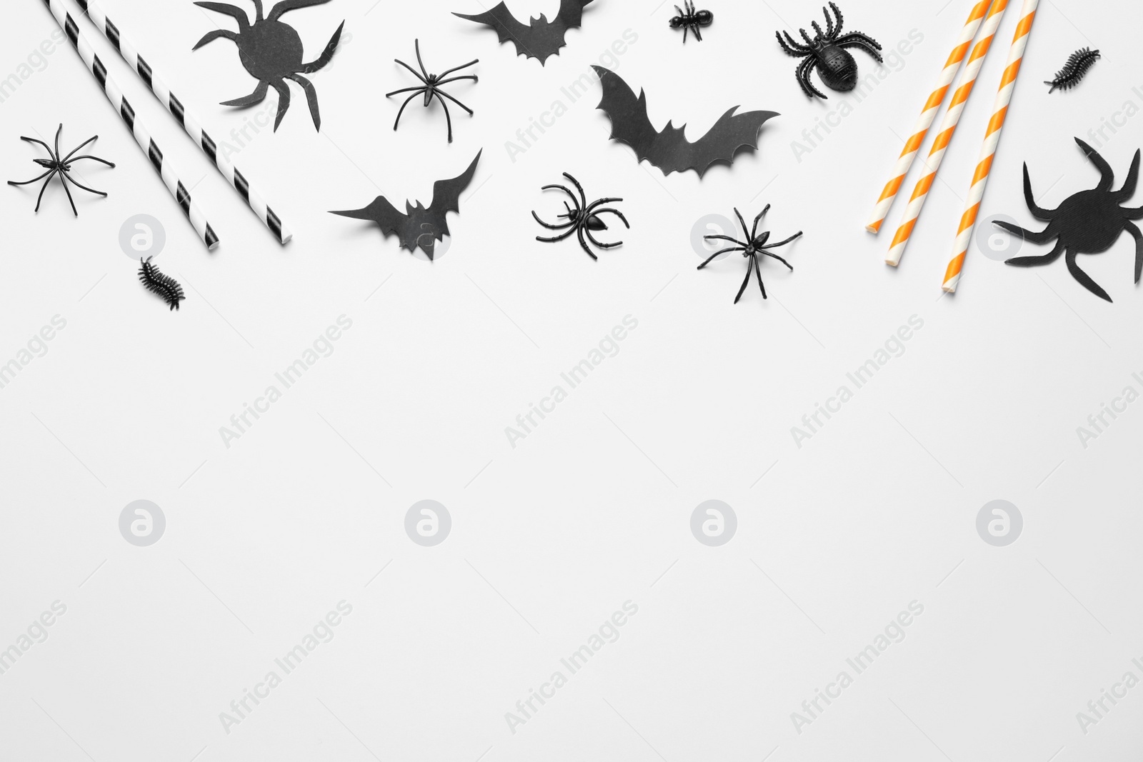 Photo of Flat lay composition with paper bats, spiders and straws on white background, space for text. Halloween celebration