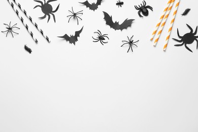 Flat lay composition with paper bats, spiders and straws on white background, space for text. Halloween celebration