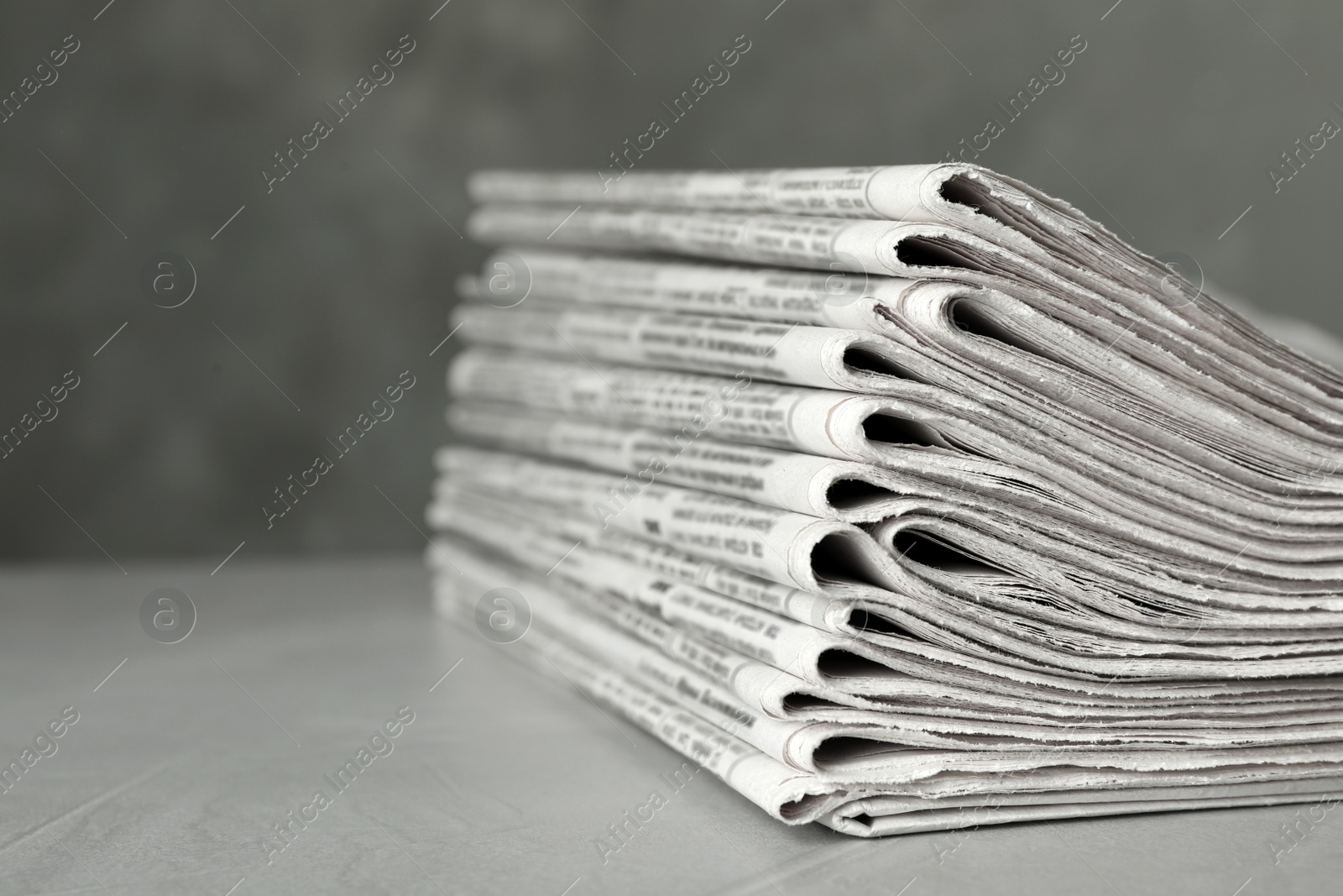 Photo of Stack of newspapers on light grey stone table, closeup. Journalist's work