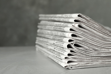 Photo of Stack of newspapers on light grey stone table, closeup. Journalist's work