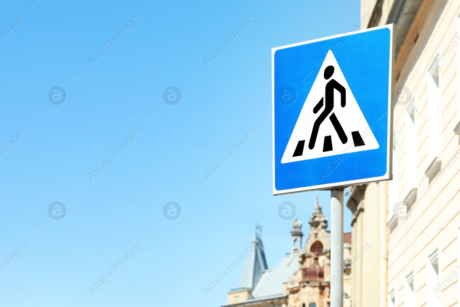 Photo of Post with Pedestrian Crossing traffic sign near building in city on sunny day