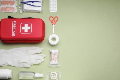 Photo of Flat lay composition with first aid kit on light green background, space for text