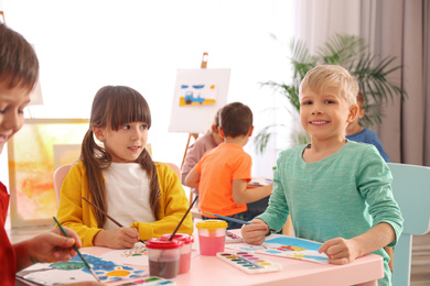 Photo of Cute little children painting at table in room