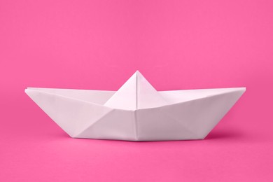 Photo of White paper boat on pink background. Origami art