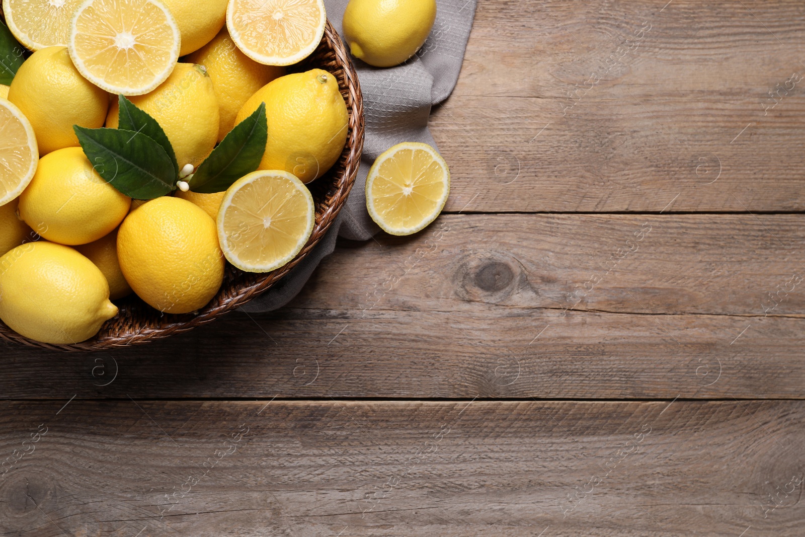 Photo of Many fresh ripe lemons with green leaves on wooden table, flat lay. Space for text