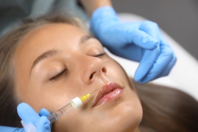 Photo of Beautiful woman getting lips injection in salon, closeup