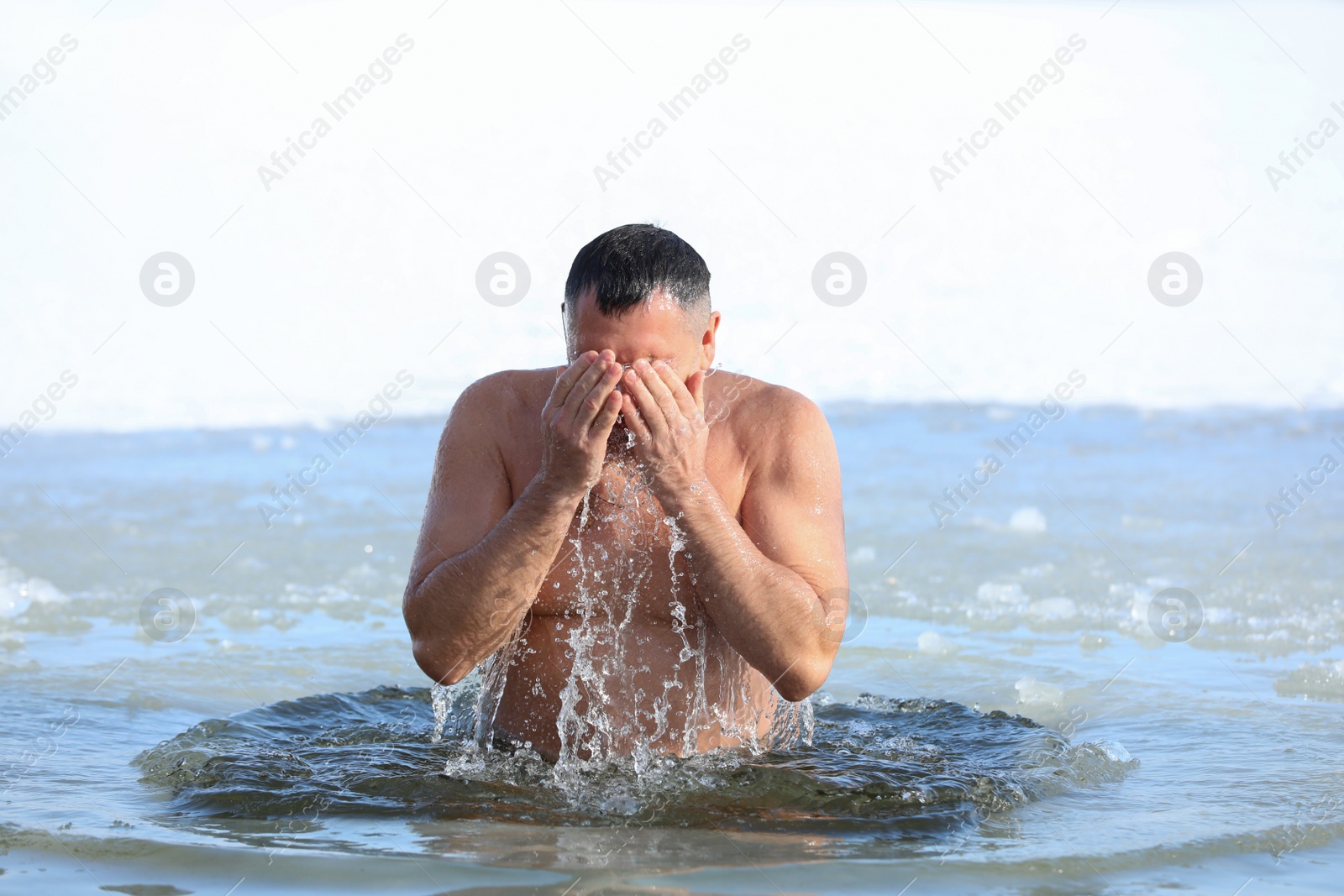 Photo of MYKOLAIV, UKRAINE - JANUARY 19, 2021: Man immersing in icy water on winter day. Traditional Baptism ritual