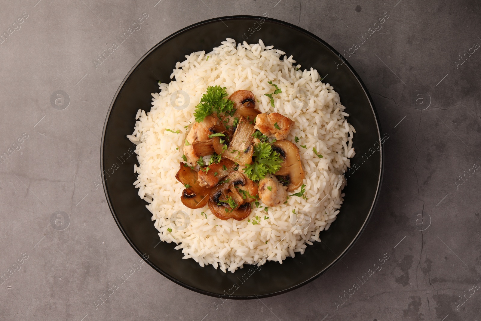 Photo of Delicious rice with parsley and mushrooms on grey table, top view