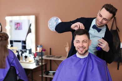 Photo of Professional hairdresser working with client in beauty salon