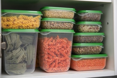 Plastic containers filled with food products in kitchen cabinet, closeup