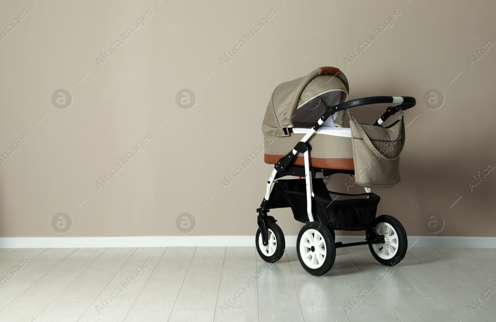 Photo of Baby carriage. Modern pram near beige wall, space for text