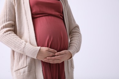 Photo of Young pregnant woman on light background, closeup. Space for text