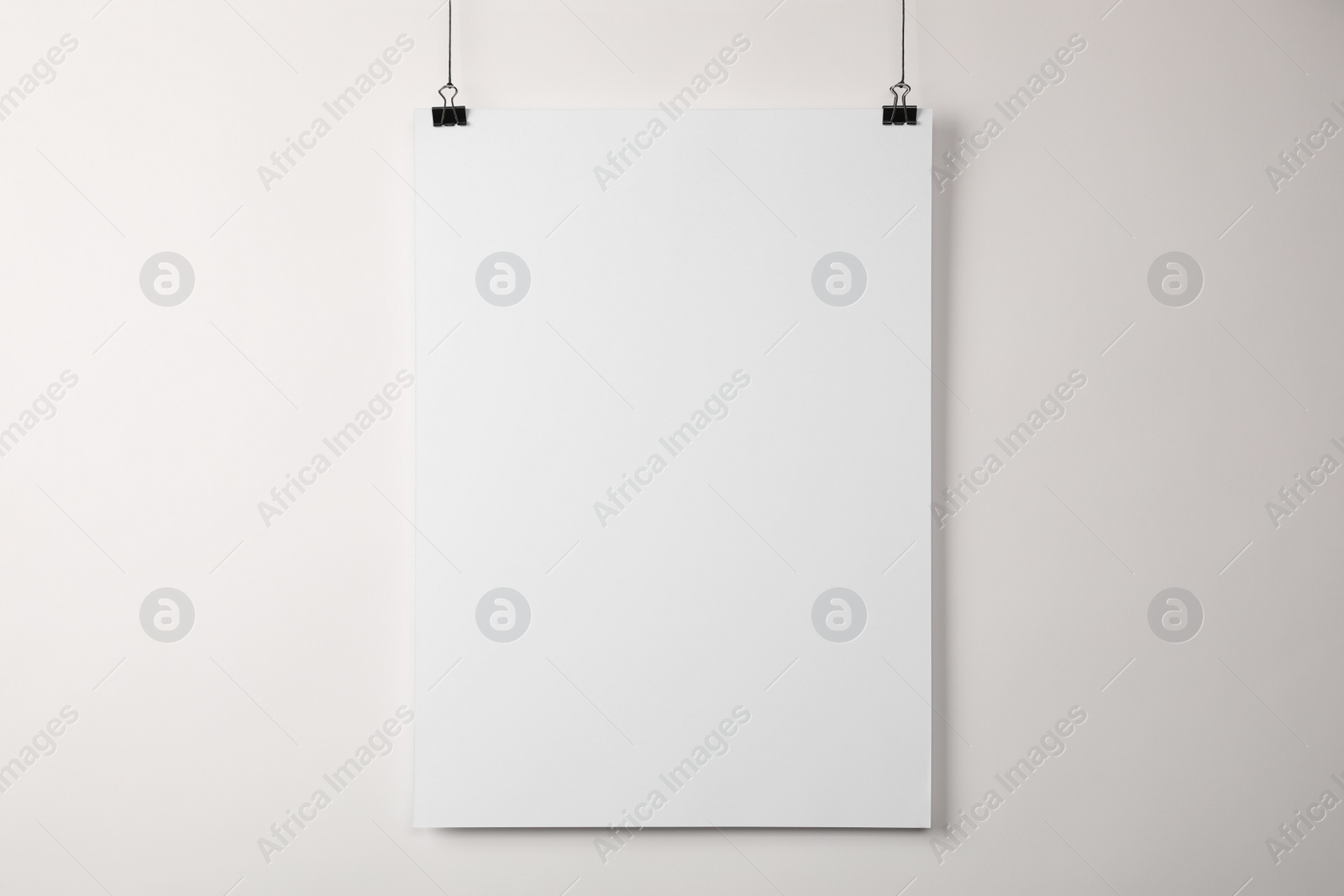 Photo of White blank poster hanging near light wall