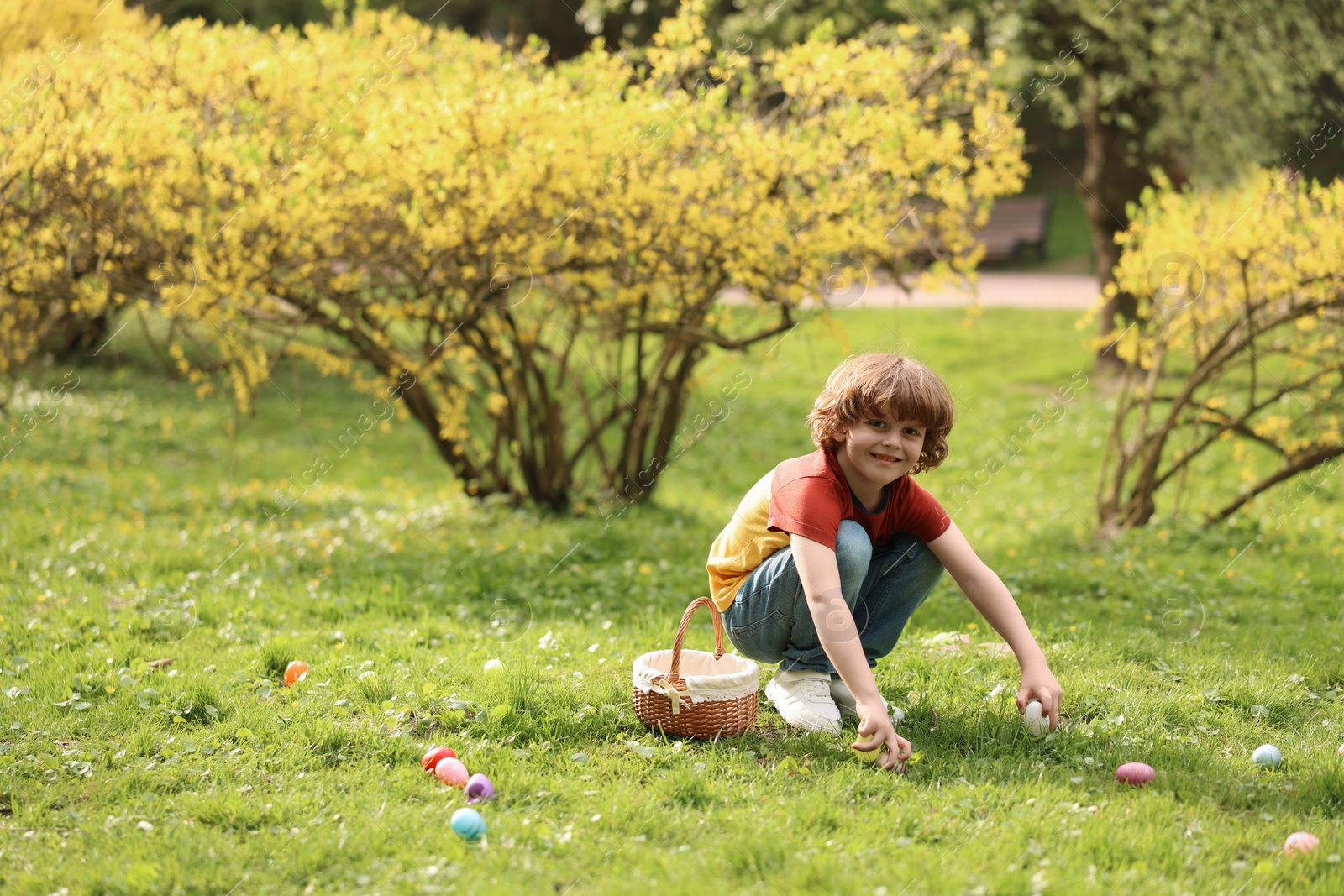 Photo of Easter celebration. Cute little boy hunting eggs outdoors, space for text