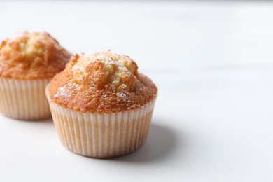 Delicious sweet muffins on white table, closeup. Space for text