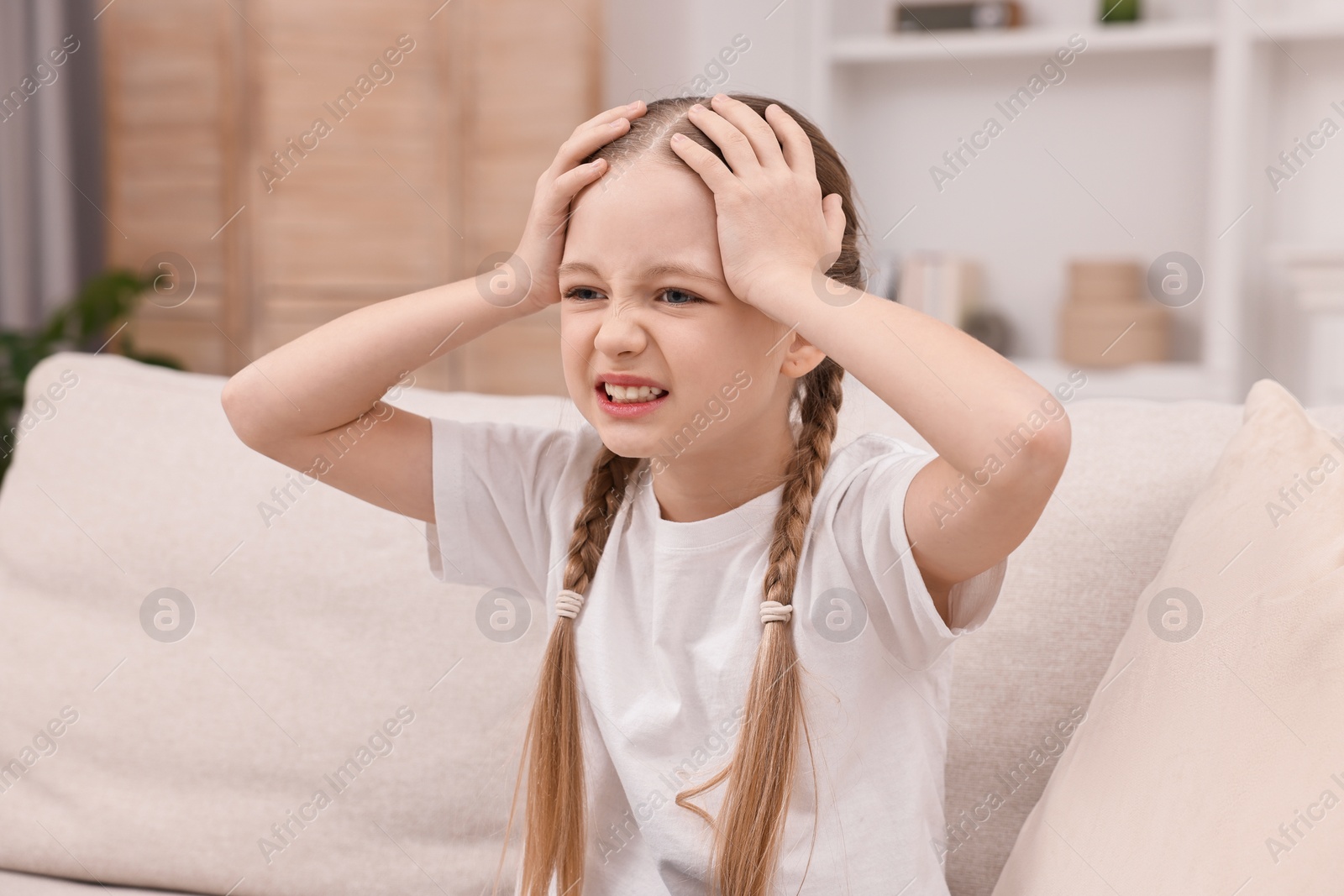 Photo of Little girl suffering from headache at home