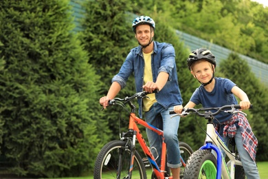 Photo of Dad and son riding modern bicycles outdoors