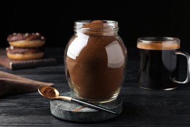 Photo of Jar of instant coffee and spoon on black wooden table