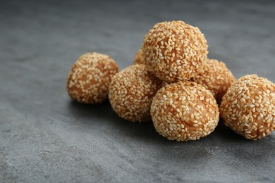 Photo of Many delicious sesame balls on grey table, closeup. Space for text