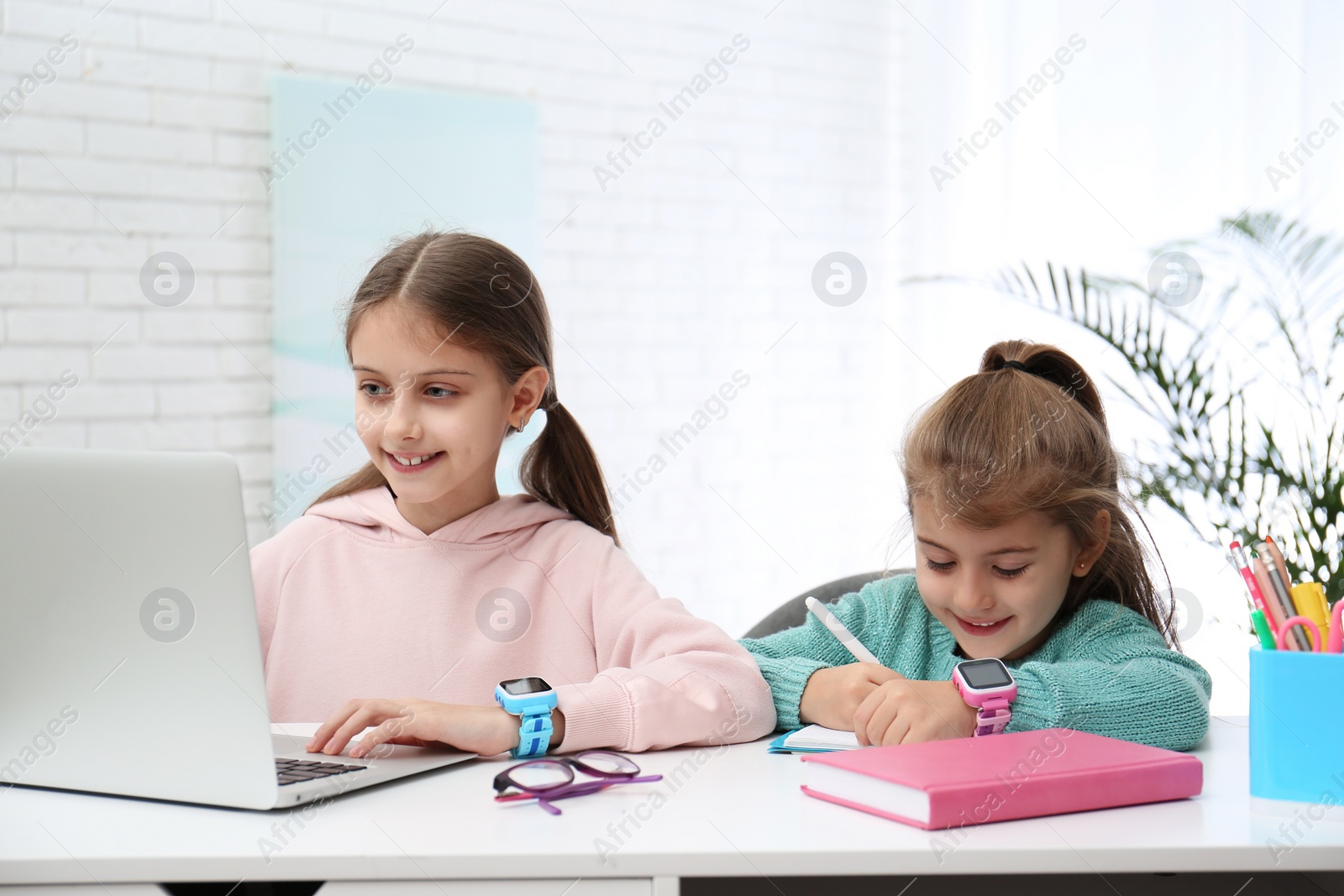 Photo of Girls with stylish smart watches at table indoors