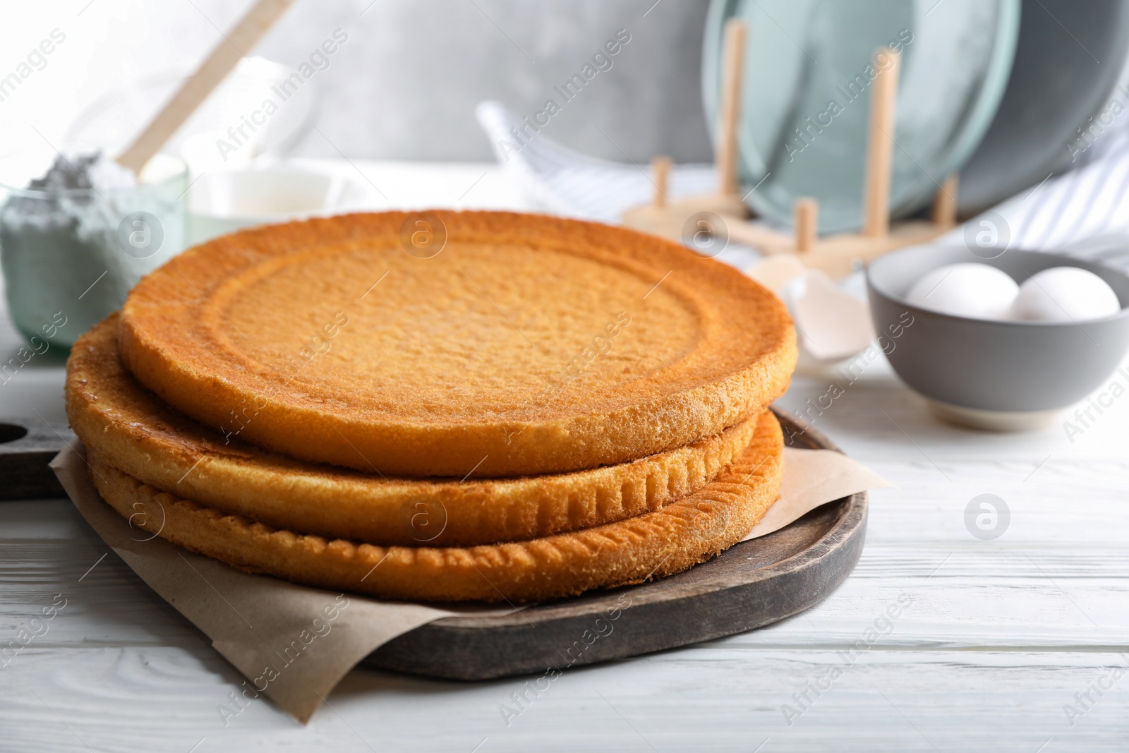 Photo of Delicious homemade sponge cakes and ingredients on white wooden table