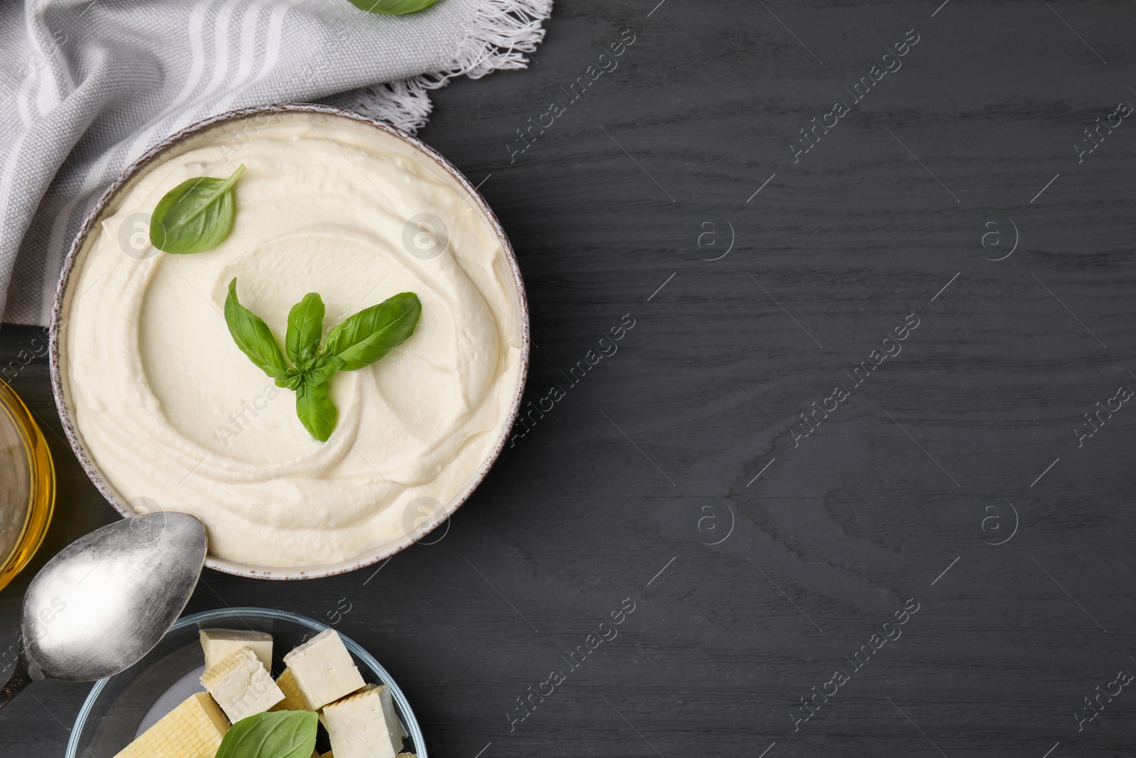 Photo of Delicious tofu sauce and basil leaves on grey wooden table, flat lay. Space for text